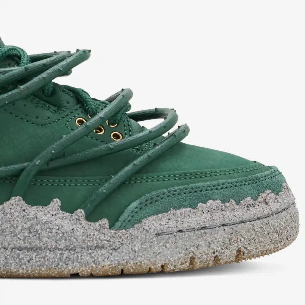 A green Teyana Taylor x Air Jordan 3 sneaker with a textured, grey speckled sole and unique lacing design.