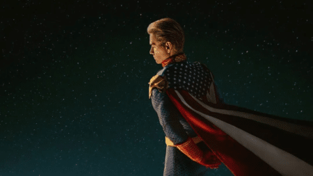 A superhero in a star-spangled suit and cape stands against a starry night sky.