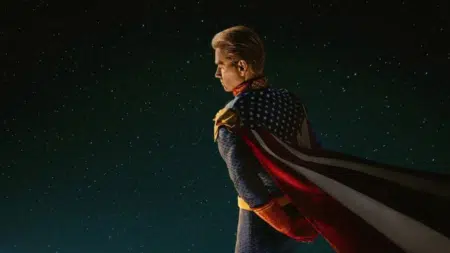 A superhero in a star-spangled suit and cape stands against a starry night sky.
