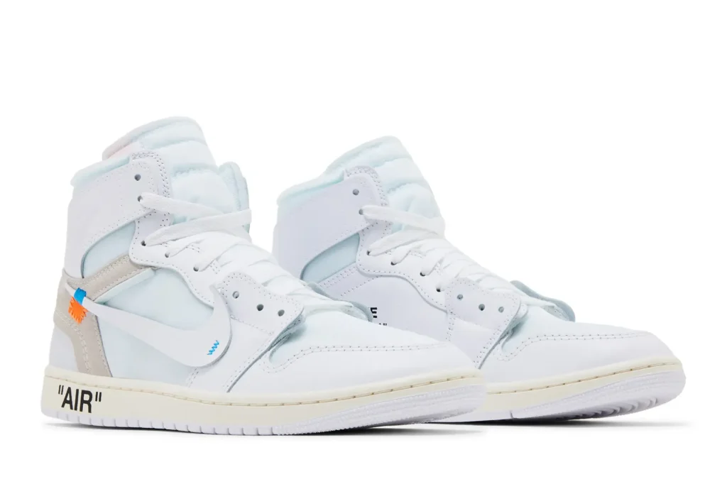 White Air Jordan 1 'Alaska' high-top sneakers with blue accents, featuring "AIR" text on the sole and distinctive side tags.