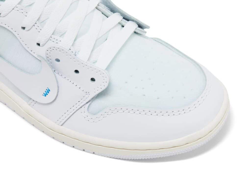 Close-up of a white Air Jordan 1 'Alaska' sneaker with a light blue toe box, perforated detailing, and white laces.