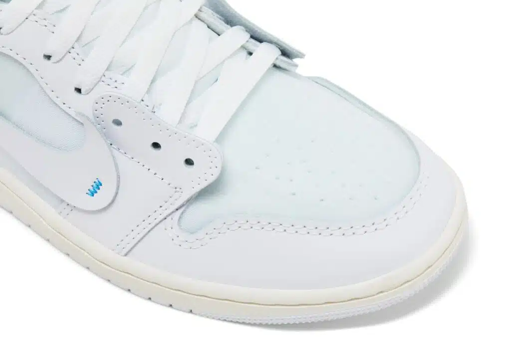 Close-up of a white Air Jordan 1 'Alaska' sneaker with a light blue toe box, perforated detailing, and white laces.