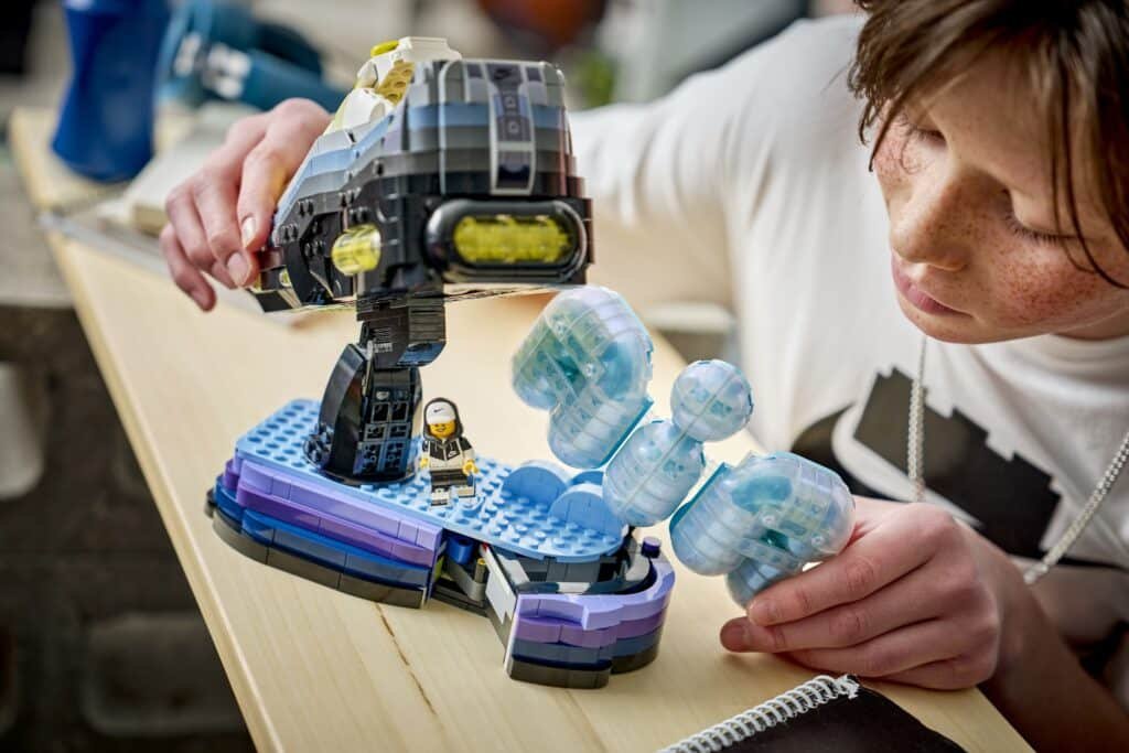 A person is playing with a space-themed LEGO set featuring a small astronaut and a large spacecraft.