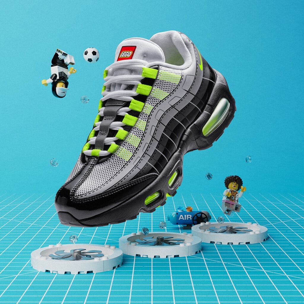 A Nike Air Max 95 x LEGO sneaker with a LEGO design and lime green accents is surrounded by Lego characters and football elements against a grid background.