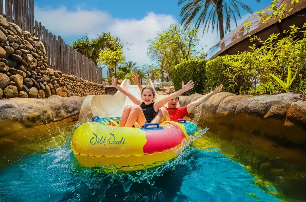 Wild Wadi Waterpark Dubai: Your Definitive Guide to Rides, Tickets & Unforgettable Family Fun Two people joyfully riding a colorful inflatable raft on a water slide at a tropical water park.