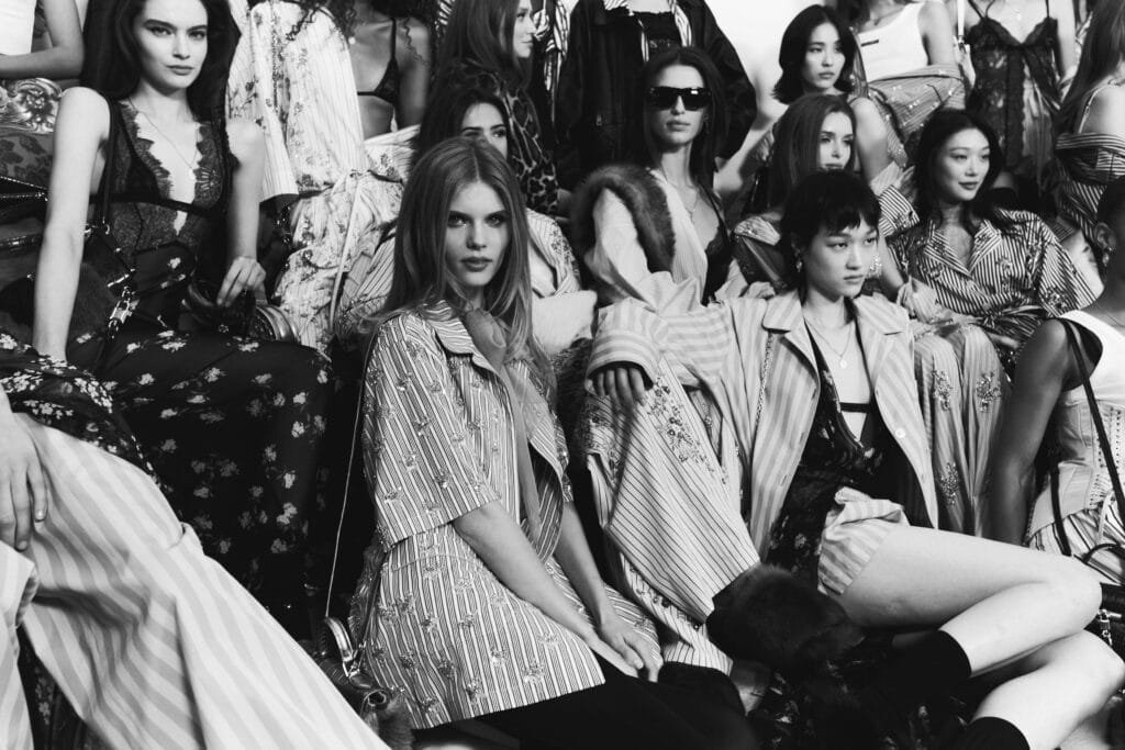 A group of models in diverse, stylish outfits pose together, featuring bold patterns and layered clothing.