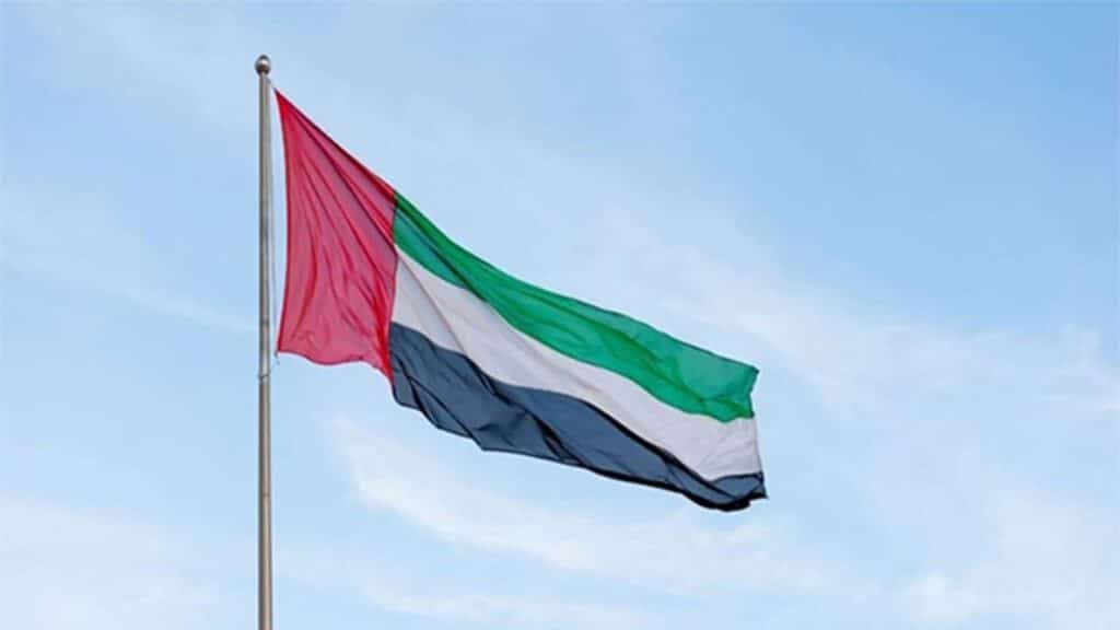 The flag of the United Arab Emirates is waving against a clear blue sky in Dubai.