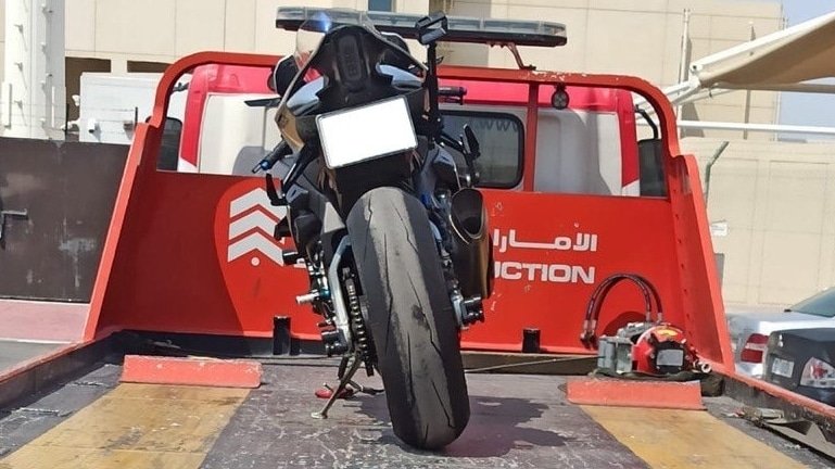 A motorcycle secured on the back of a red tow truck.