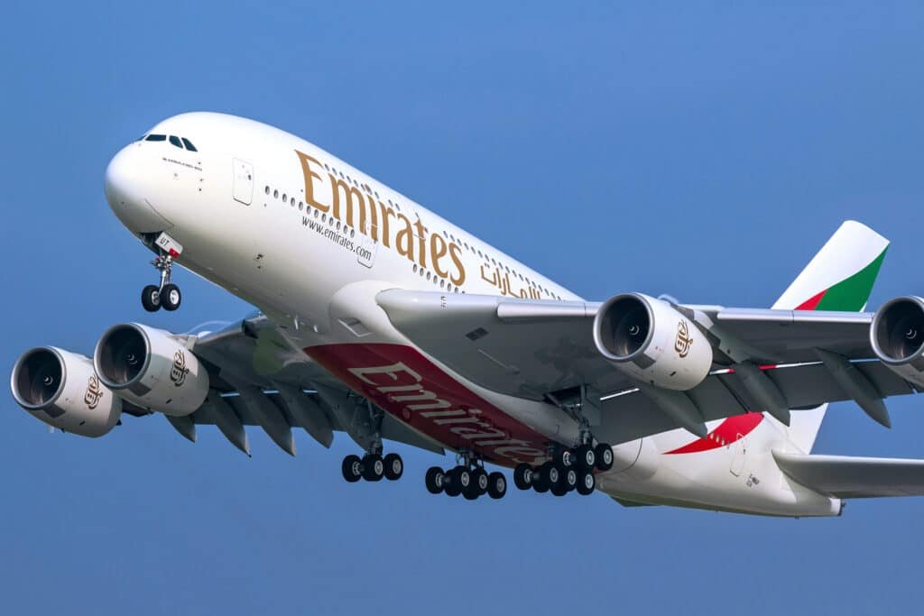 A large Emirates A380 aeroplane in flight with landing gear extended.