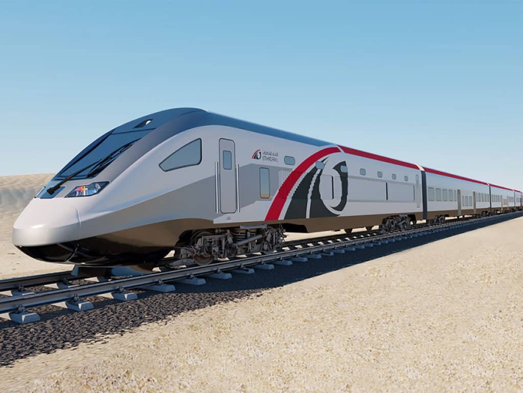 A modern high-speed train with a sleek design and distinctive red and black accents on a desert track under a clear blue sky.