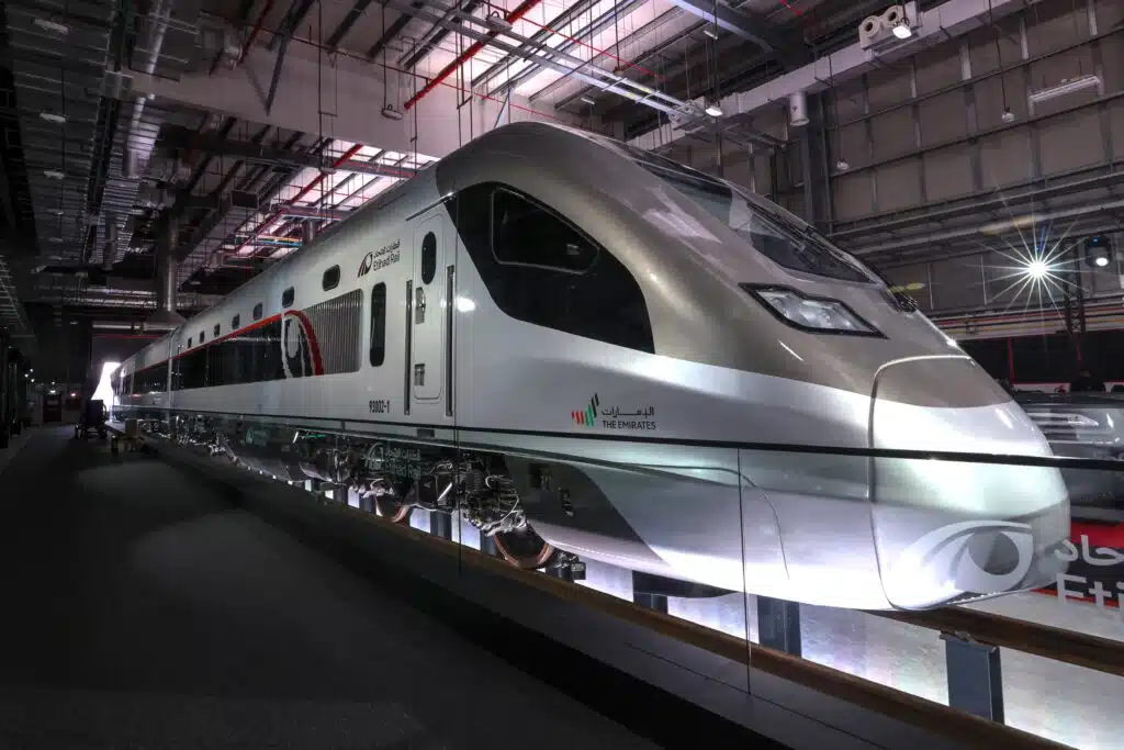 A sleek, modern high-speed train is on display inside a large, well-lit industrial facility.
