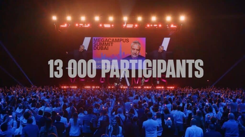 A large audience faces a stage with a screen displaying "Megacampus Summit Dubai" and "13,000 Participants" in bold text.