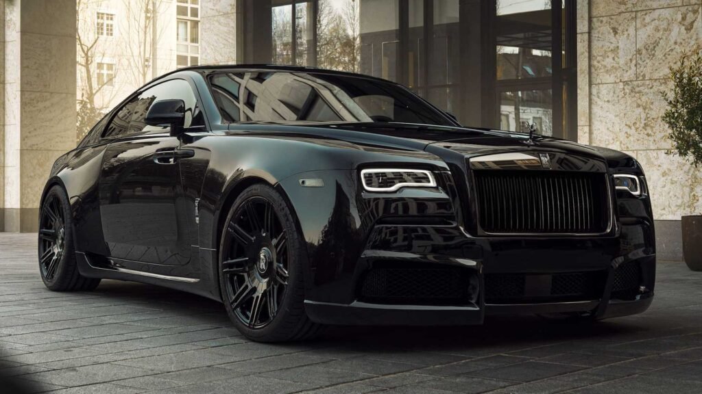 A sleek Rolls-Royce Black Badge luxury coupe is parked on a city street in front of a modern building.