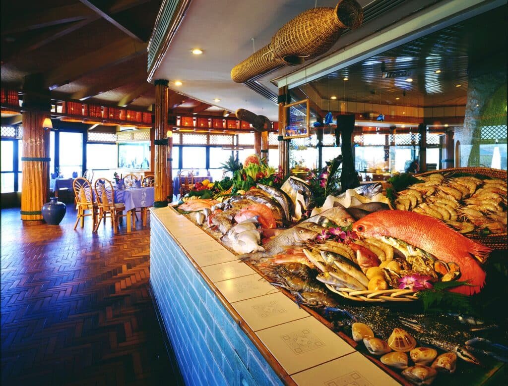 Best Seafood Restaurants on Abu Dhabi Corniche: A seafood buffet with a variety of fish and shellfish displayed on a large table in a restaurant with wooden decor.