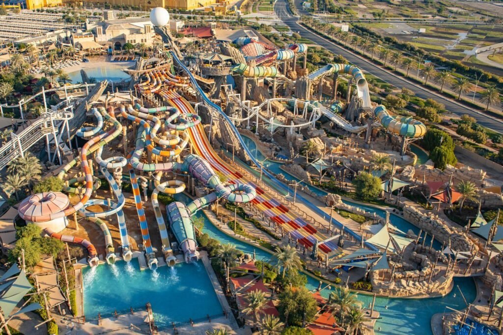 An aerial view of Yas Waterworld Abu Dhabi with numerous colorful water slides, pools, and surrounding greenery.
