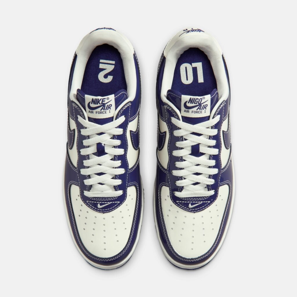 A pair of white and dark blue Nike x NIGO Air Force 1 LO2 sneakers viewed from above, showing the company logo on the tongue and insoles.