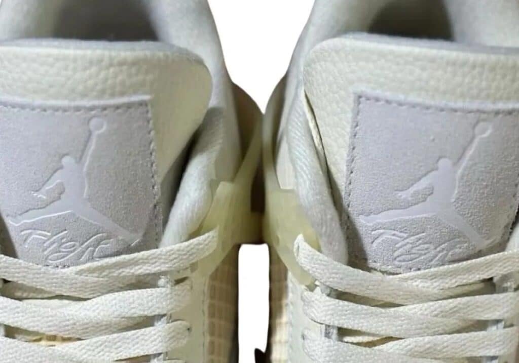 A pair of white athletic shoes with a visible logo featuring a jumping figure.
