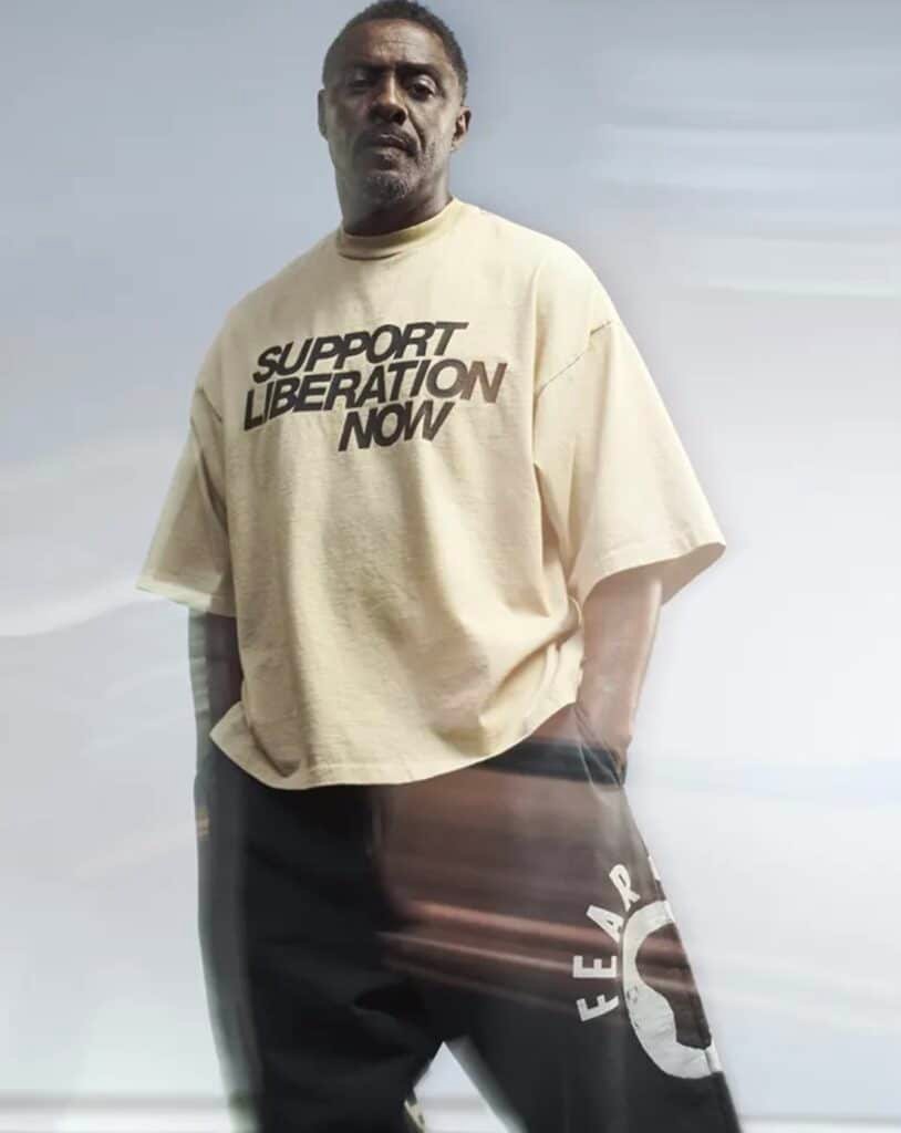 Idris Elba wearing a beige Fear of God x Idris Elba Tee