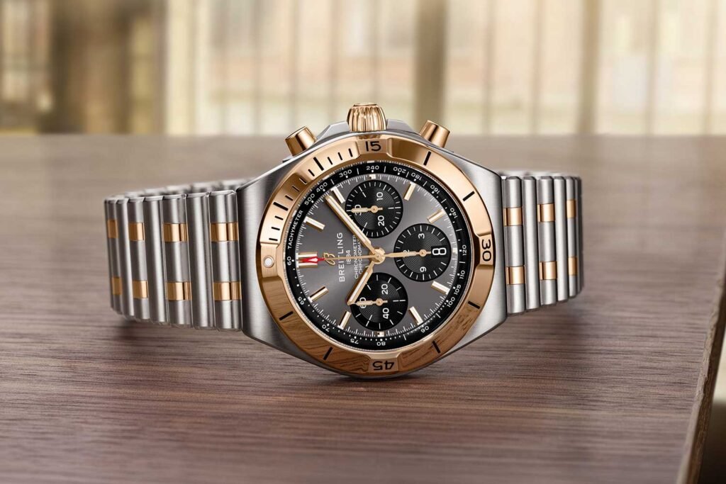 Luxury stainless steel and gold chronograph wristwatch on a wooden table, displayed front-facing