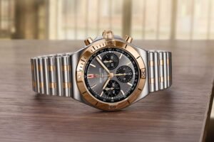 Luxury stainless steel and gold chronograph wristwatch on a wooden table, displayed front-facing