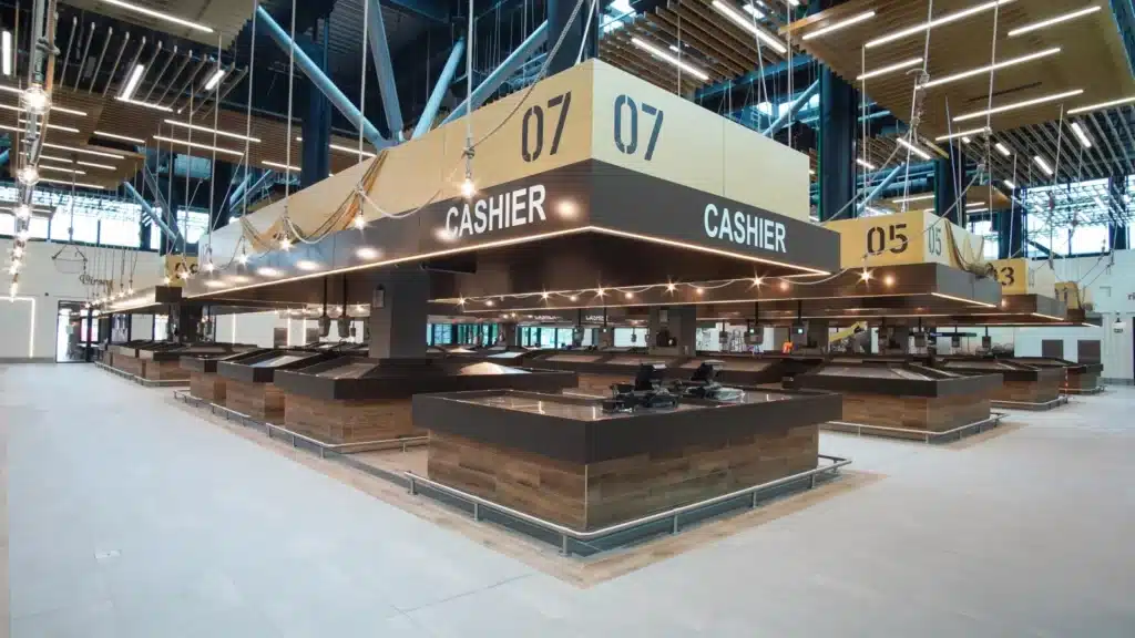 An empty modern food court with multiple cashier stations numbered 05, 06, and 07 under bright lighting.