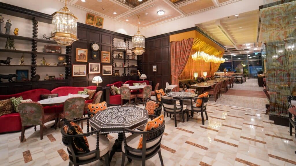 A luxurious restaurant interior with ornate chandeliers, elegant seating, and decorative shelves on the wall.
