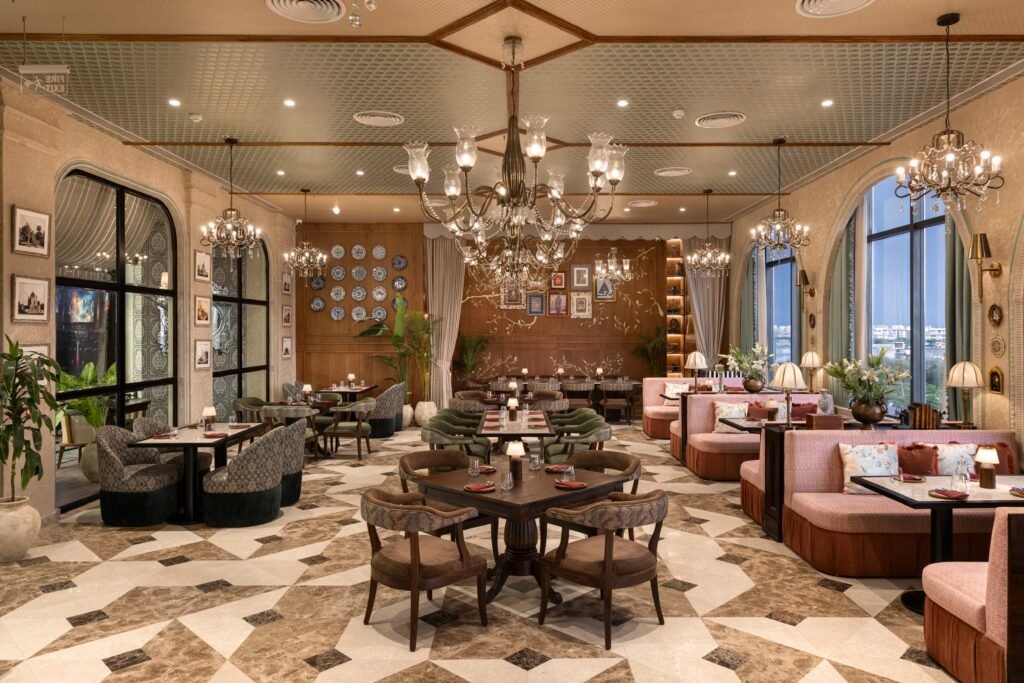 Elegant Pincode By Kunal Kapur restaurant interior with chandelier lighting, patterned floor tiles, plush seating, and framed art on the walls.