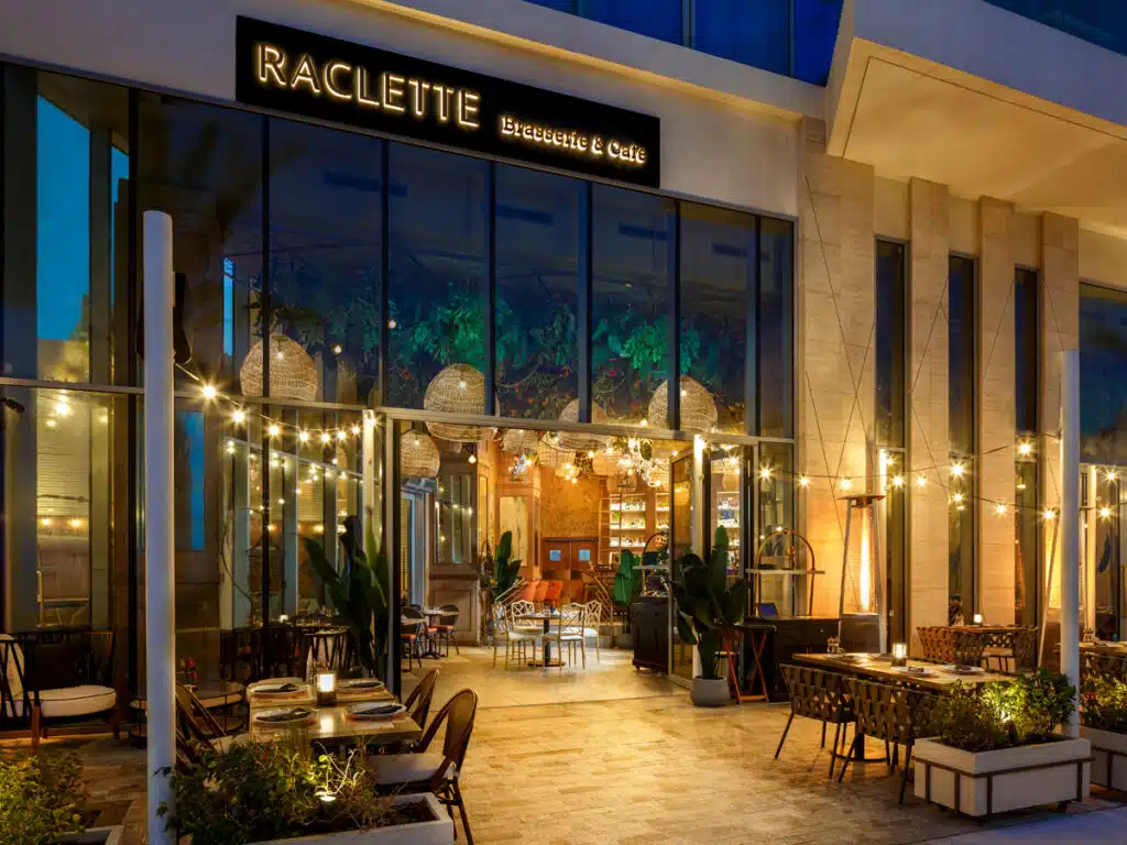 Outdoor patio of Raclette Brasserie & Cafe with string lights, tables, and warm evening ambiance