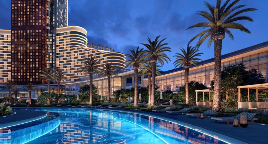 A luxurious resort with a palm-lined pool area and modern skyscrapers, illuminated at dusk.