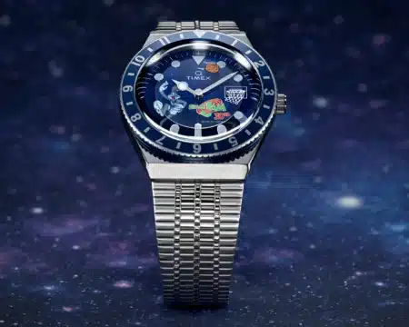 A wristwatch with a silver metal band and a blue dial featuring colorful Space Jam themed graphics and a basketball hoop.