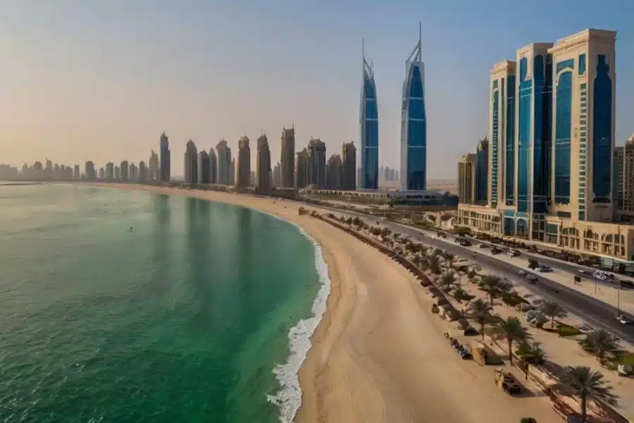 Curved beach beside a coastal skyline of modern high-rise towers at sunset