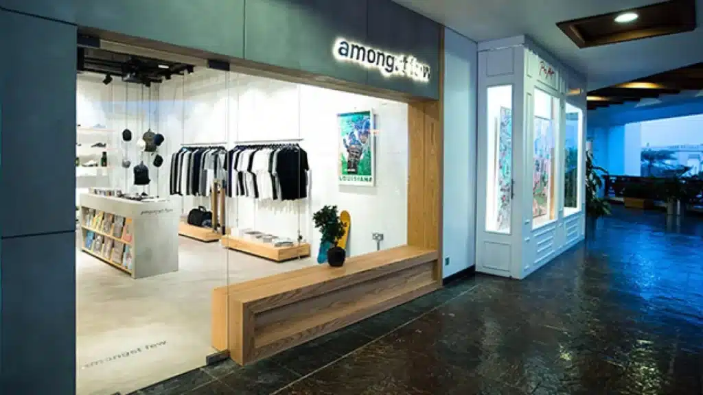 Modern clothing boutique storefront in a mall hallway, with racks of black-and-white shirts and bright display shelves