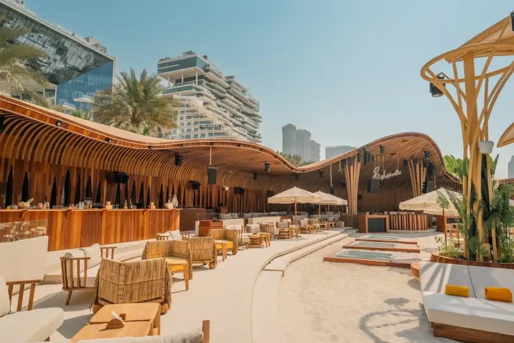 Modern beachfront lounge with curved wooden canopy, sandy seating area, and city high-rises in the background