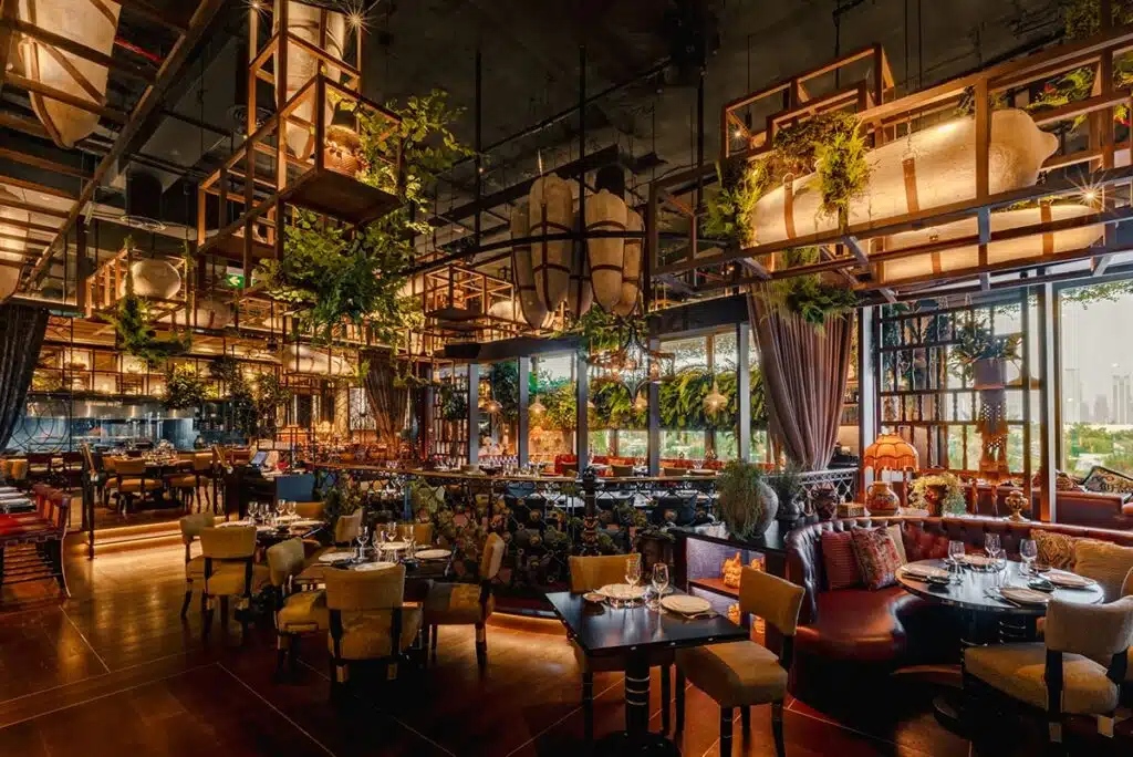 Best Brunch in Dubai: Upscale Coya restaurant interior with warm lighting, hanging plants, and set tables near large windows
