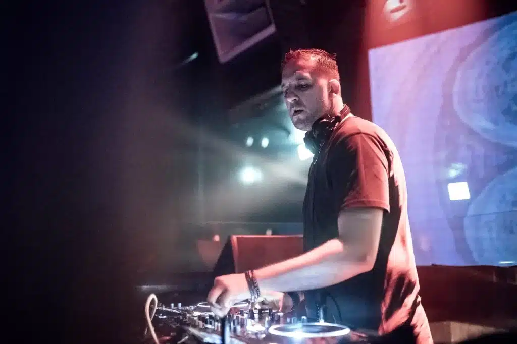 Darko De Jan: The Sound Architect of Dubai’s Luxury Nightlife DJ mixing music at a club console under colorful stage lights