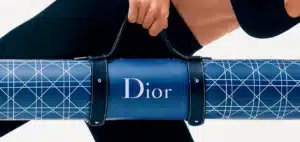 Person carrying a blue Dior yoga mat with geometric white lines