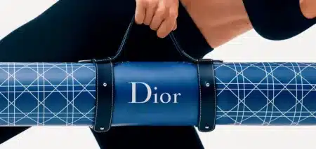 Person carrying a blue Dior yoga mat with geometric white lines