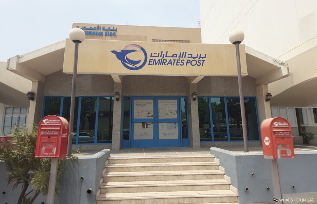 Why Dubai Has No Postcodes (And Exactly How to Send Mail Here) Emirates Post building entrance with blue doors, steps, and two red letter boxes