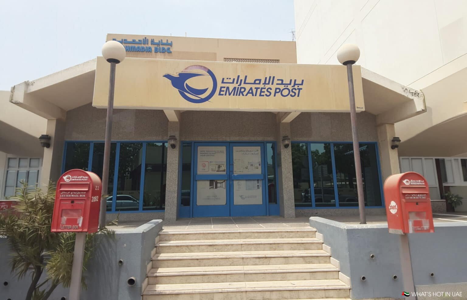 Emirates Post building entrance with blue doors, steps, and two red letter boxes