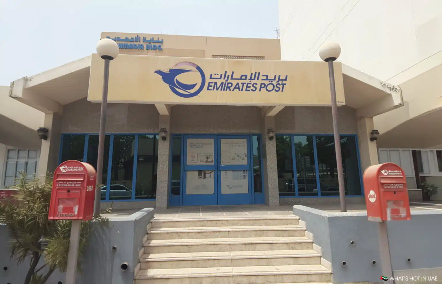 Emirates Post building entrance with blue doors, steps, and two red letter boxes
