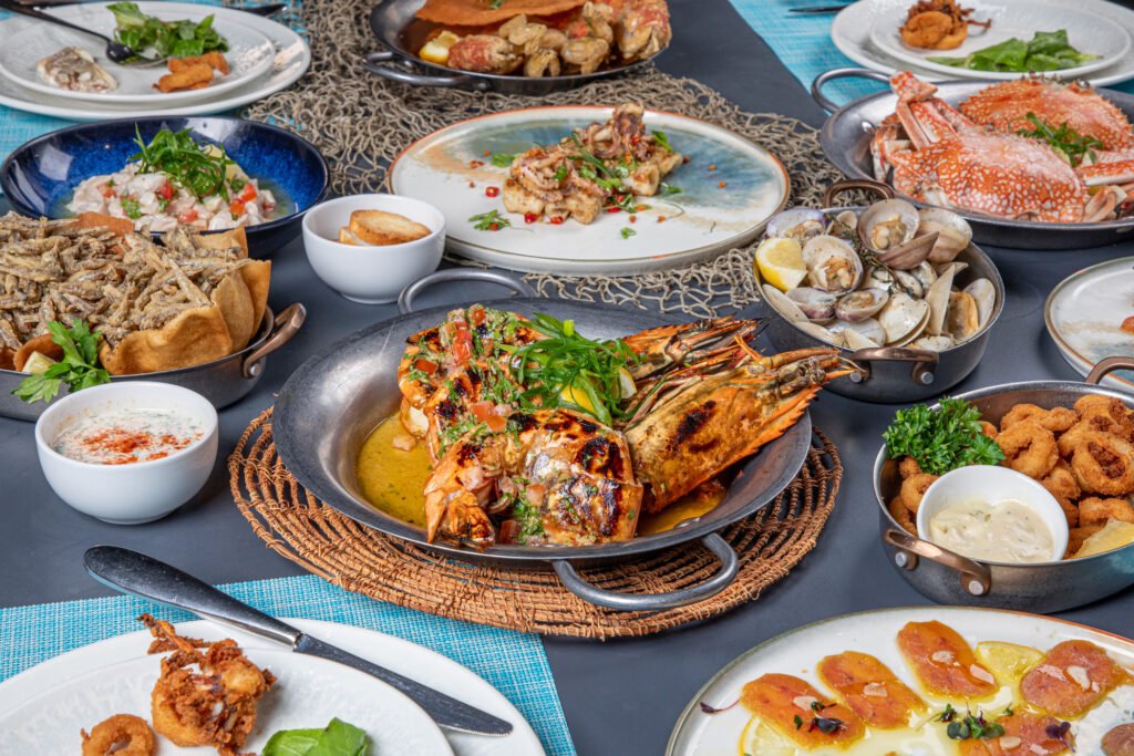 Best Brunch in Dubai: Assorted seafood dishes on a table, including grilled prawns, crab, clams, calamari, and fried fish with sauces