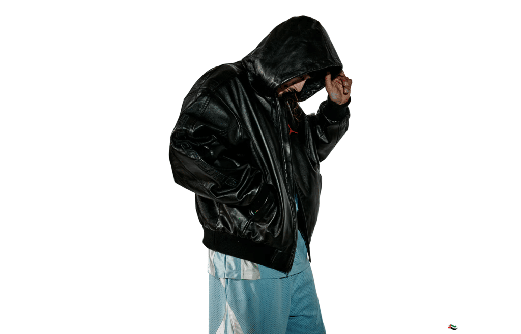 Person in a black Supreme x Jordan Brand Spring 2026 hooded jacket and light blue pants, standing against a white background with head bowed