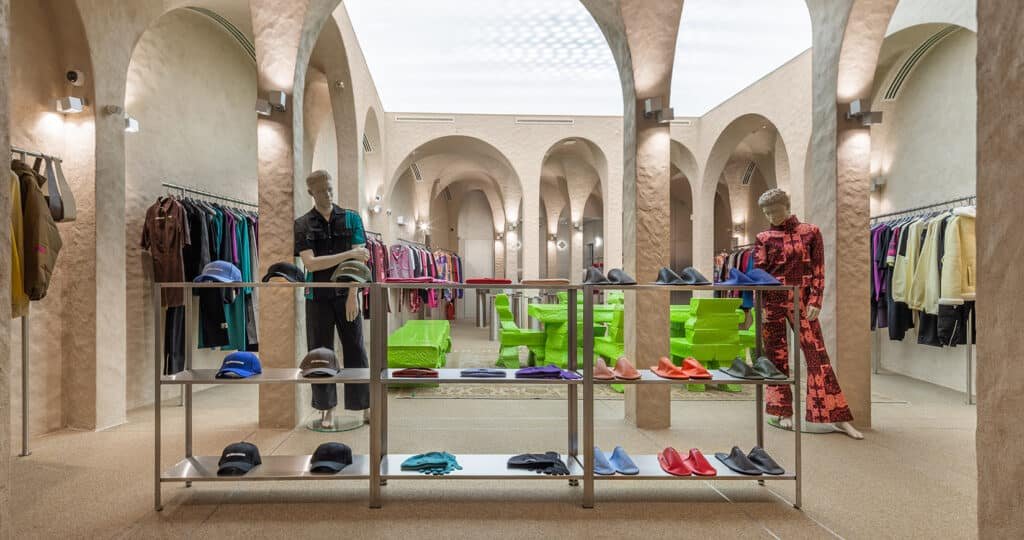 Modern boutique interior with arched ceilings, mannequins, and colorful clothing and shoes on display racks