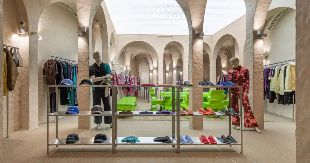 Modern boutique interior with arched ceilings, mannequins, and colorful clothing and shoes on display racks