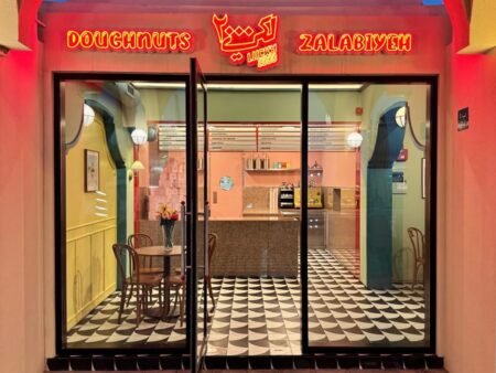 Colorful doughnut and zalabieh shop entrance with neon signage and patterned black-and-white floor