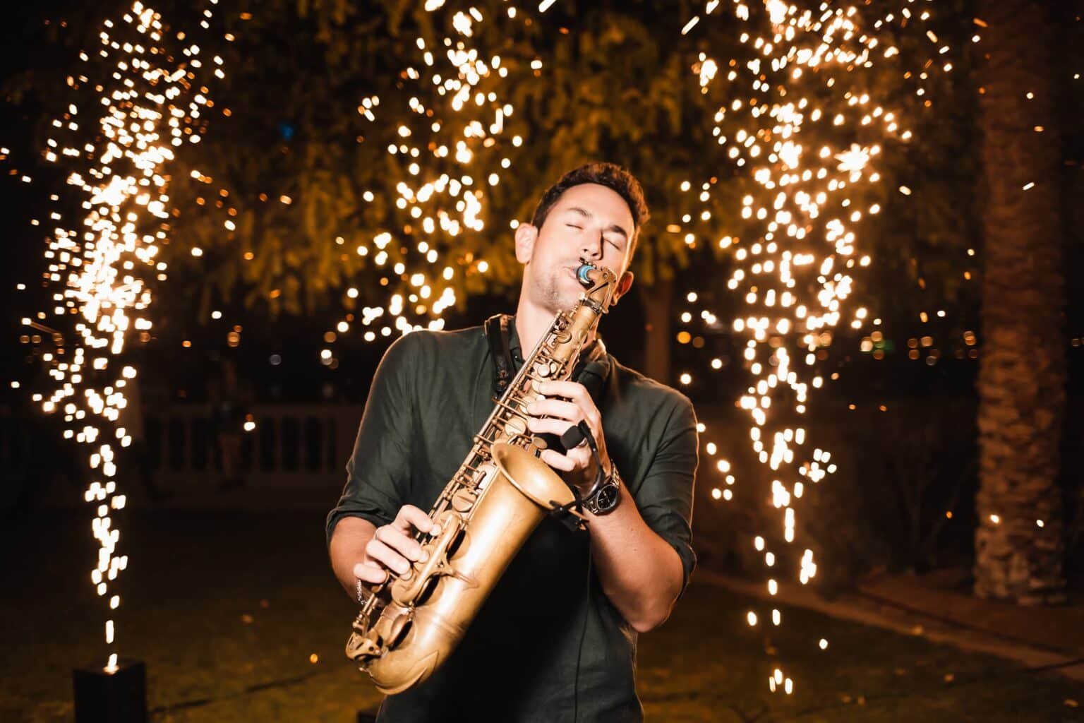 A man playing a saxophone amid bright fireworks at night