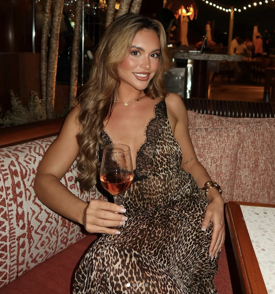 Ladies Night: Smiling woman in a leopard-print dress holding a glass of rosé at a dimly lit lounge