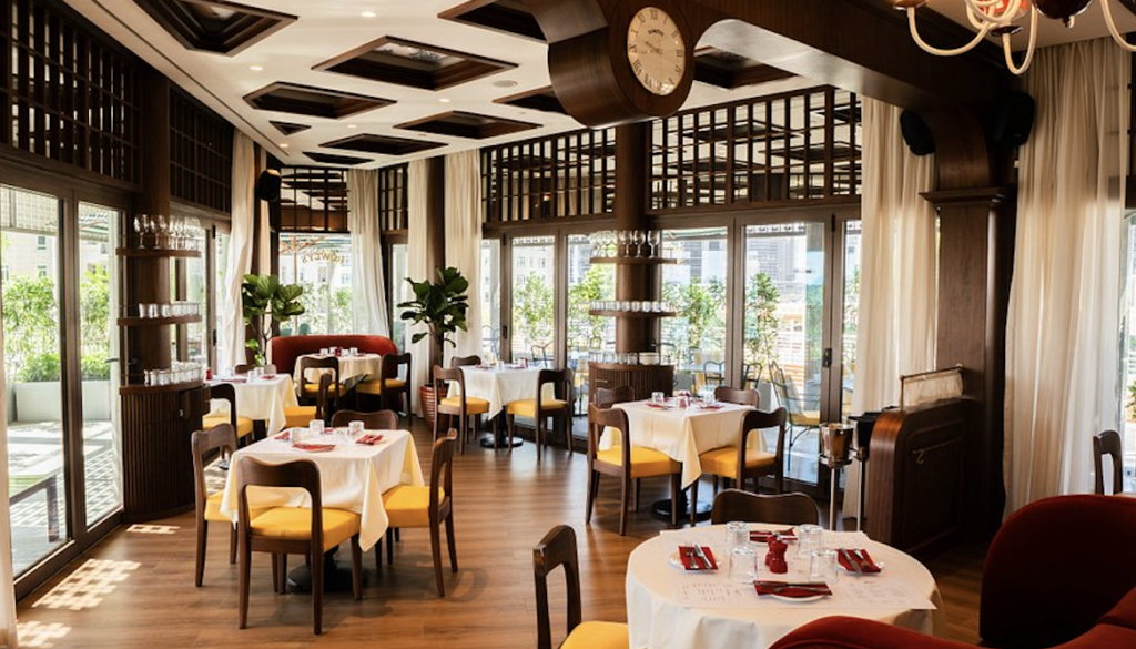 Bright, elegant restaurant dining room with set tables, yellow chairs, and large windows