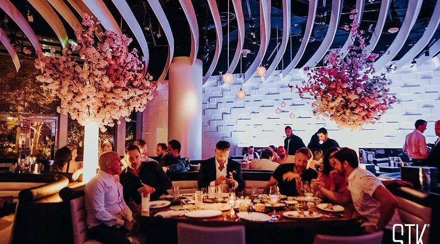 Guests dining at a stylish restaurant with floral ceiling decor and warm ambient lighting