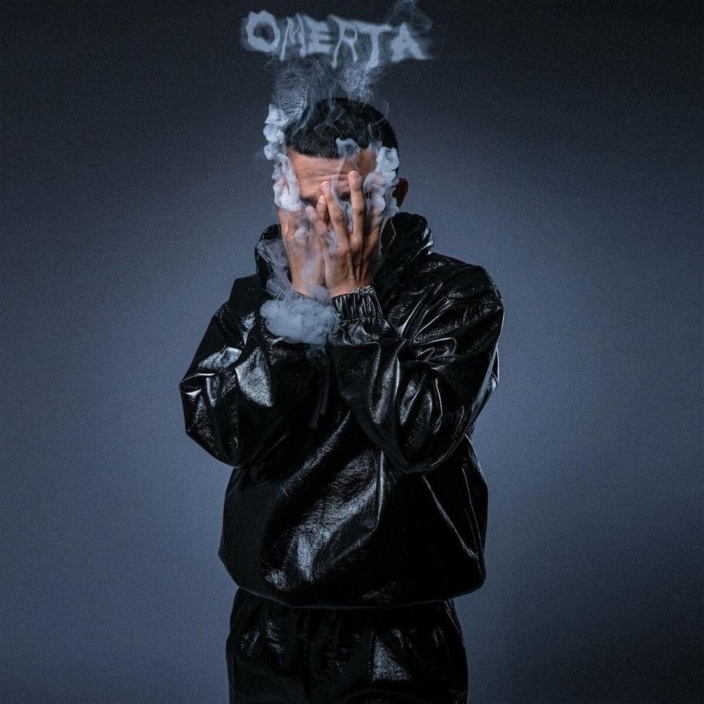7ARI in a shiny black outfit covering their face with smoke rising around them against a dark background